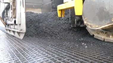 Yeni asfalt tabakasını yavaşça döşeyen bir paten. Kırsal alanda yol yapan özel makineler. Sıkıştırıcı otoyol yapımı. Ağır makineler yolu onarıyor. Yol çalışması süreci. Yol onarımı.