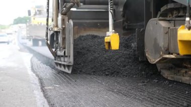 Kırsal alanda yol yapan özel makineler. Sıkıştırıcı otoyol yapımı. Ağır makineler yolu onarıyor. Yeni asfalt tabakasını yavaşça döşeyen bir paten. Yol çalışması süreci. Yol onarımı.