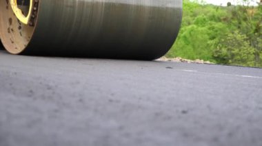 Sıkıştırıcı otoyol yapımı. Steamroller yavaşça sürüyor. Ağır makinelerle yol onarımı. Paten yeni asfalt tabakası seriyor. Yol yapımı özel makineler. Yol çalışması ve otoyol bakımı kavramı