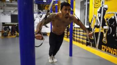 Genç Afro-Amerikan sporcu spor kulübünde trx ekipmanları üzerinde egzersiz yapıyor. Modern spor salonunda sıkı çalışan Afrikalı kaslı bir sporcu. Fitness merkezinde çalışan güçlü bir zenci. Sportif yaşam tarzı.