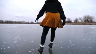 Bulutlu bir günde donmuş nehirde buz pateni yapan kadın patenci. Doğada buz pateni pistinde kayan artistik paten giymiş bir kadın. Soğuk kış havasında pratik yapan genç bir kız. Kış mevsiminde aktif boş zaman.