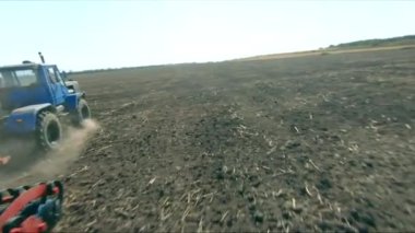 Tarımsal tarım arazisinde tarla sürme sistemi olan traktörün hava görüntüsü. Arkasındaki toz parçalarıyla hasat edildikten sonra tarlayı işliyor. Tarım makinesi tarım arazisinden geçiyor.