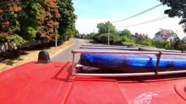 Şehir yolundaki yangın yerine giderken mavi ışıklı büyük kırmızı bir kamyonet. İtfaiye aracı şehir caddesinde acil durum yerine gidiyor. Hayat kurtarmak ve kahramanlık mesleği kavramı. Üst görünüm.