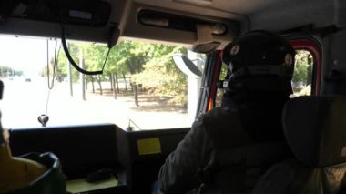 Professional fireman in uniform riding on a big truck to place of a fire. Young male firefighter in full equipment driving on fire engine to an emergency. Concept of saving lives and heroic profession