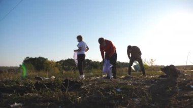 Yetişkin ve küçük gönüllüler yol kenarındaki çimenlikte çöp topluyor. Çevre aktivistlerinin ailesi kırsal bölgelerdeki plastik ve kağıt atıklarını temizliyor. Yardım doğası kavramı. Dolly vurdu..