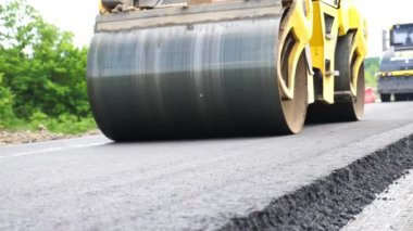 Sıkıştırıcı otoyol yapımı. Steamroller yavaşça sürüyor. Ağır makinelerle yol onarımı. Paten yeni asfalt tabakası seriyor. Yol yapımı özel makineler. Yol çalışması ve otoyol bakımı kavramı