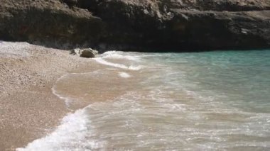 Güneşli bir günde kumsala vuran deniz dalgalarının sakin manzarası. Güzel deniz manzarası. Sahil şeridini yıkayan berrak okyanus suyunun yumuşak gelgitleri. Boş deniz kenarında manzara manzarası. Seyahat konsepti. Yavaş çekim.