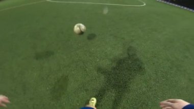 Futbolcunun akşam saatlerinde futbol sahasında antrenman yapmasına bakış açısı. Adam topa sürüp rakibine vurmaya çalışıyor. Adam topu arkadaşına atıyor. Boş zaman konsepti. POV.
