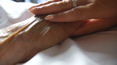 Annesinin şefkatini ya da sevgisini gösteren elini nazikçe okşayan tanınamaz bir kadın. Klinikte yatan yaşlı bir annenin kırışık kolunu rahatlatan kızı. Kız, eski ailesine destek oluyor. Ayrıntılı görünüm