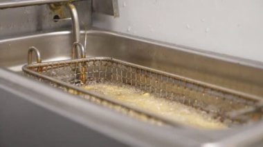 Çıtır patates kızartması mutfakta kızartma yapıyor. Lezzetli patatesler mutfakta kızgın yağda kızartılıyor. Fast food yapma süreci. Yemek hazırlama kavramı. Yavaşça kapat..