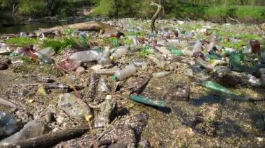 Nehir birçok plastik şişeyle kirlidir. Pek çok çöp doğadaki açık ve serbestçe ulaşılabilir yerlere atılır. Küresel çevre kirliliği sorunu. Ekolojik felaket kavramı.