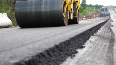 Paten yeni asfalt tabakası seriyor. Yol yapımı özel makineler. Sıkıştırıcı otoyol yapımı. Steamroller yavaşça sürüyor. Ağır makinelerle yol onarımı. Yol çalışması ve otoyol bakımı kavramı