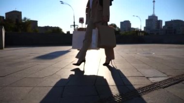 Genç kız şehir caddesinde yürüyen kağıt paketler taşıyor. Güzel bir kadın alışveriş sonrası alışveriş çantalarını şehir meydanında tutuyor. Satış ve indirim kavramı. Düşük görünüm Yavaş çekim Yakın çekim.