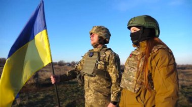 Ukrayna bayrağı sallayan Ukrayna ordusunun askerleri. Üniformalı askerler mavi gökyüzüne bayrak kaldırdı. Rus saldırısına karşı zafer. İstila direnci konsepti. Yavaş çekim.