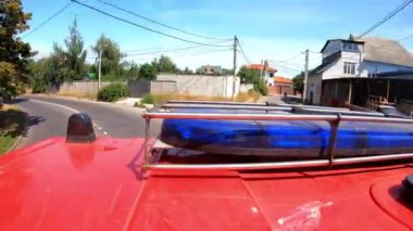 Şehir yolundaki yangın yerine giderken mavi ışıklı büyük kırmızı bir kamyonet. İtfaiye aracı şehir caddesinde acil durum yerine gidiyor. Hayat kurtarmak ve kahramanlık mesleği kavramı. Üst görünüm.