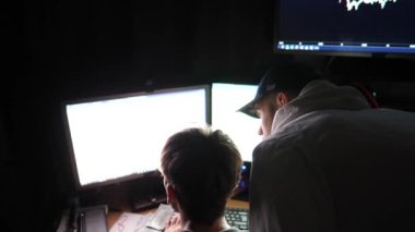 Grafikleri ve döviz çizelgelerini analiz eden iki genç borsa simsarı. Akşam vakti finans analistlerinin takım çalışması. Bağımsızlar geceleri çalışır. Bitcoin BTC ve kripto ticareti kavramı.
