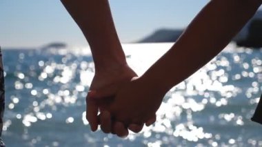 Okyanus kıyısında el ele tutuşan genç çift. Tropikal tatil boyunca birlikte zaman geçiren iki güzel sevgili. Sevgi ve mutluluk kavramı. Arka plan Yavaş çekim.