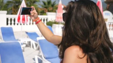 Çekici esmerler akıllı telefonda selfie portresi çekiyorlar. Yaz tatilinde fotoğraf çeken kaygısız genç kadınlar. Kamerada poz veren güzel bayanlar. İki kız arkadaş birlikte dinleniyor. Yavaş çekim.