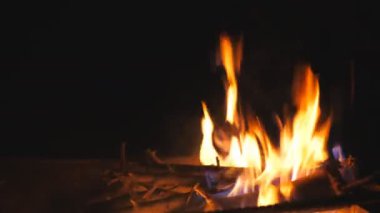 Mangalda yanan odun ve kömürden yükselen parlak alevlerin kapağı siyah arka planda. Yakacak odun ve kömür geceleri barbeküde yanar. Sıcaklık ve sükunet kavramı. Ağır çekim..