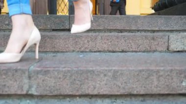 Kot pantolonlu kadın bacakları ve merdivenlerden inen yüksek topuklu ayakkabılar. İnce ayaklı çekici bir kız merdivenlere basıyor. Genç bir kadın merdivenlerden iniyor. Şehir caddesinde yürüyen bir kız. Yavaş çekim.