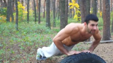 Güçlü ve kaslı bir adam ormanda şınav çekiyor. Erkek sporcu doğada egzersiz yapıyor. Atletik adam dışarıda antrenman yapıyor. Spor anlayışı ve aktif yaşam tarzı. Yavaş çekim Dolly yakın çekim.