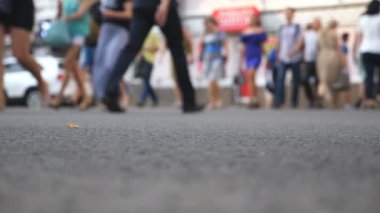 Büyük şehirde yaz günü, tanınmayan yayaların kavşaktan karşıya geçerken alçak açılı görüntüsü. Şehir merkezinde yaya geçidinde yürüyen bir kalabalık. Kentsel yaşam tarzı kavramı. Bulanık hareket. Yavaş çekim.