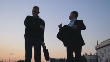 Başarılı iş anlaşması sonra şehir sokak yürürken evrak çantaları komik dans ile iki mutlu genç işadamlarının kapatın. Neşeli arkadaşları günbatımı'nda başarı kutluyor. Düşük açılı görünüş