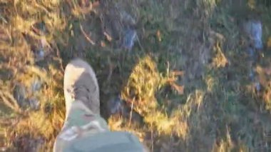 Tarlada koşan, asker ayakkabılı genç bir kızın bacaklarına bakış açısı. Kırsal kesimdeki kuru çimlerin arasında kahverengi çizmelerle koşan Ukrayna askerinin kadın ayağı. Ukrayna 'da Savaş.
