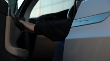 Adam kapıyı açıyor ve modern arabadan iniyor. Adam otomobilin kapısını açtı. Elektrikli otomotiv çıkışı. İş seyahati ya da anlaşma. Çağdaş teknolojiler kavramı. Yavaş Hareketi Kapat.