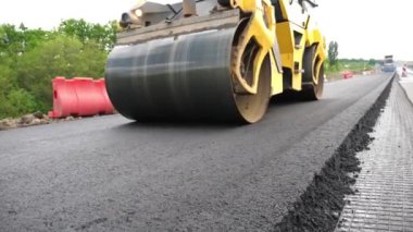 Sıkıştırıcı otoyol yapımı. Steamroller yavaşça sürüyor. Ağır makinelerle yol onarımı. Paten yeni asfalt tabakası seriyor. Yol yapımı özel makineler. Yol çalışması ve otoyol bakımı kavramı