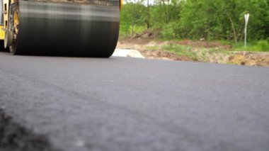 Sıkıştırıcı otoyol yapımı. Steamroller yavaşça sürüyor. Ağır makinelerle yol onarımı. Paten yeni asfalt tabakası seriyor. Yol yapımı özel makineler. Yol çalışması ve otoyol bakımı kavramı