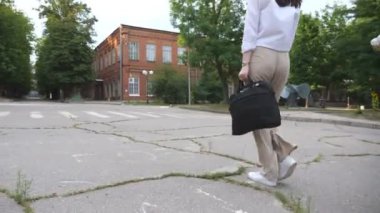 Resmi kıyafetli genç iş kadını şehir parkından geçiyor. Çalışma gününden sonra evrak çantalı bir ofis çalışanı eve dönüyor. Dışarıda yürüyen güzel bir kız. Kariyer ya da iş kavramı. Ağır çekim..