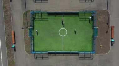 Yaz günü şehir parkındaki çağdaş spor sahalarında hava manzarası. Gençler, gençler ve çocuklar modern oyun alanlarında futbol ve basketbol oynuyorlar. Sağlıklı bir yaşam tarzını popülerleştirme kavramı.