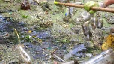 Kirli gölde enkaz toplayan kauçuk giysili tanınmayan çevreci aktivist. Koruyucu eldivenlerle çöpleri temizleyen gönüllü erkeklerin elleri. Çevre kirliliği koruması kavramı.