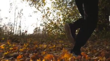 Sonbahar parkta çalışan tanınmayan sporcu, Kuru akçaağaç yaprakları üzerinde adım. Renkli düşmüş yaprakları üzerinde erkek Runner jogging. Doğada genç atlet eğitimi. Sağlıklı yaşam konsepti. Arka görünüm.