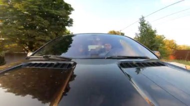 Genç çift iletişim kuruyor ve araba yolculuğunun tadını çıkarıyor. Erkek arkadaş ve kız arkadaş yaz akşamı otomobille seyahat ediyorlar. Yolculuk kavramı. Ön görünümü kapat.