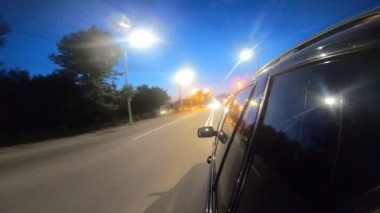 Gece şehir otobanında siyah bir cip sürüyormuş. Akşamları otomobille şehir sokaklarında dolaşmak. Araç otoban boyunca hızla ilerliyor. Arka planda manzaralı şehir trafiği. Yolculuk konsepti. POV.