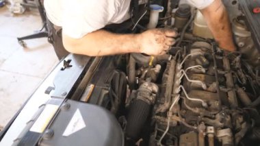 Kirli eller tamirci atölyede ya da serviste arabanın motorunu tamir ediyor. Otomobil tamircisi garajda araç kontrol motoru altında çalışıyor. Bakım ve otomobil kontrolü kavramı. Yavaş çekim