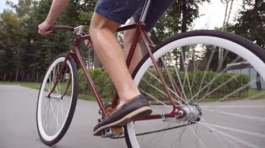Klasik bir bisiklete binen tanınmamış genç adam. Parkta bisiklete binen sporcu çocuk. Sağlıklı aktif yaşam tarzı. Düşük açı. Ağır çekim..