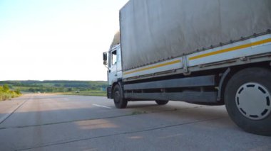 Kamera, otoyolda giden kamyonu takip ediyor. Kamyon arka planda güzel bir manzarayla kırsal alanda ilerliyor. Asfaltta araba turu. Yan Görünüm Yavaş çekim Kapat.