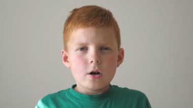 Sevimli çocuk kameraya zevkle bakar ve şaşırır. Kapalı alanda çilli yakışıklı bir çocuğun portresi. Genç bir çocuk yüzünde şok ve şaşkınlık ifadesi ile kafasını sıkıca tutuyor. Ağır çekim. Yaklaş..