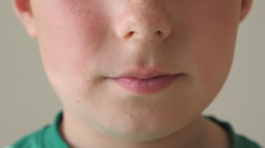 Genç, yakışıklı çocuk ağzını kapat. Çocuk yüzündeki detay görüntüsü. Yavaş çekim.
