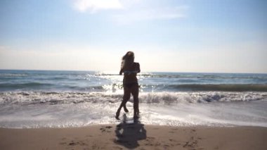 Elele ve sahil üzerinde iplik kadın ve genç erkek. Neşeli çift birlikte güneşli bir günde çevresinde swirling. Mutlu çifti kumsalda eğleniyor aşık. Yaz tatili ya da tatil. Ağır çekim.