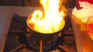 Tanınmayan şef otel restoranında flaşlı yemek pişiriyor. Erkek bir aşçı turistler için sabah gaz tabağında sebze kızartıyor. Yemek hazırlama konsepti. Kapat..