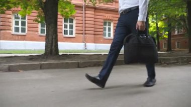 Resmi olarak genç ofis çalışanlarının bacakları şehir caddesinde güvenli adımlarla yürürler. İş merkezine giderken çantası olan başarılı bir adamın ayakları. Müdür dışarıda yürüyor. Yavaş çekim. Yakın çekim..