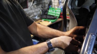 Tamircinin erkek elleri, işyerindeki aletleri kullanarak motorun motorunu tamir ediyor. Atölyede motor tamir eden profesyonel tamirci kolları. Garajda çalışan yetişkin bir tamirci. Yavaş çekim.