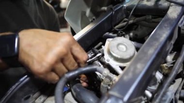 Tamircinin erkek elleri, işyerindeki aletleri kullanarak motorun motorunu tamir ediyor. Atölyede motor tamir eden profesyonel tamirci kolları. Garajda çalışan yetişkin bir tamirci. Yavaş çekim.