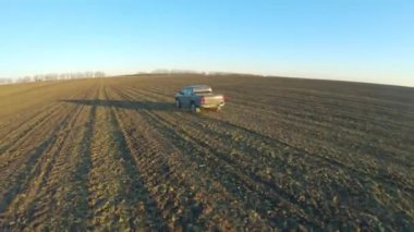 Gündüz vakti tarlalar arasında araba hareket ediyor. Hasattan sonra tarladan geçen bir kamyonet. Güneşli bir günde çayır boyunca giden off-road aracı. Tarım çiftçiliği kavramı. Hava görüntüsü.