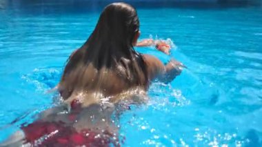 Tanımlanamayan seksi kadın şeffaf temiz suyla havuza dalıyor. Genç kız yaz tatili boyunca havuzda dinleniyor. Yaz tatili kavramı. Yavaş çekim Arka plan.