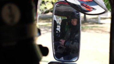 Young fireman reflecting in side mirror of moving big truck. Professional firefighter in full equipment riding on fire engine to an emergency. Concept of saving lives and heroic profession. Close up.